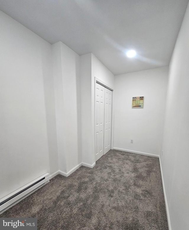 interior space featuring a baseboard heating unit and dark carpet