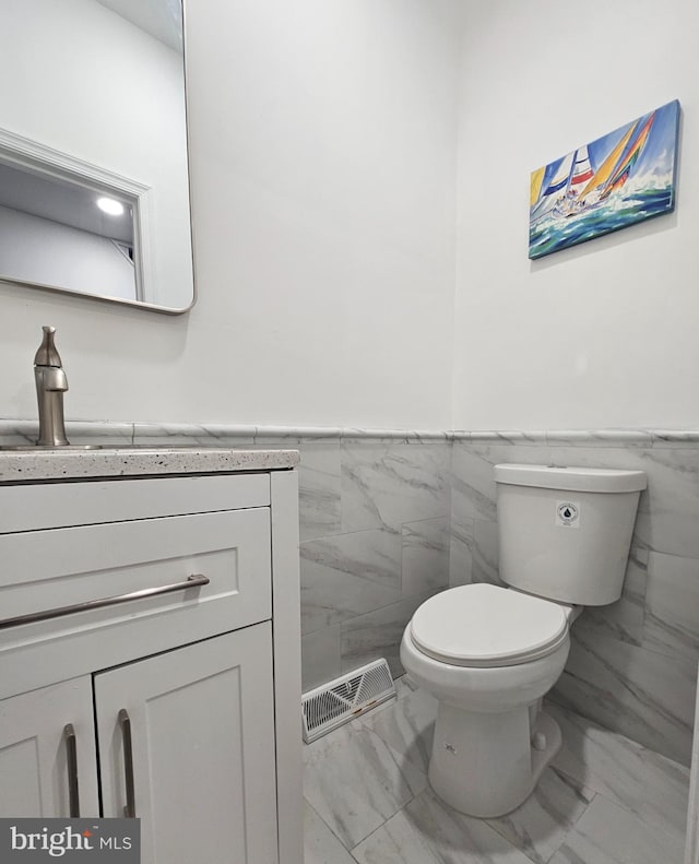 1005 N Spruce St, Wilmington, DE 19801 - bathroom featuring marble look tiles, tile walls, toilet, vanity, and a wainscoted wall