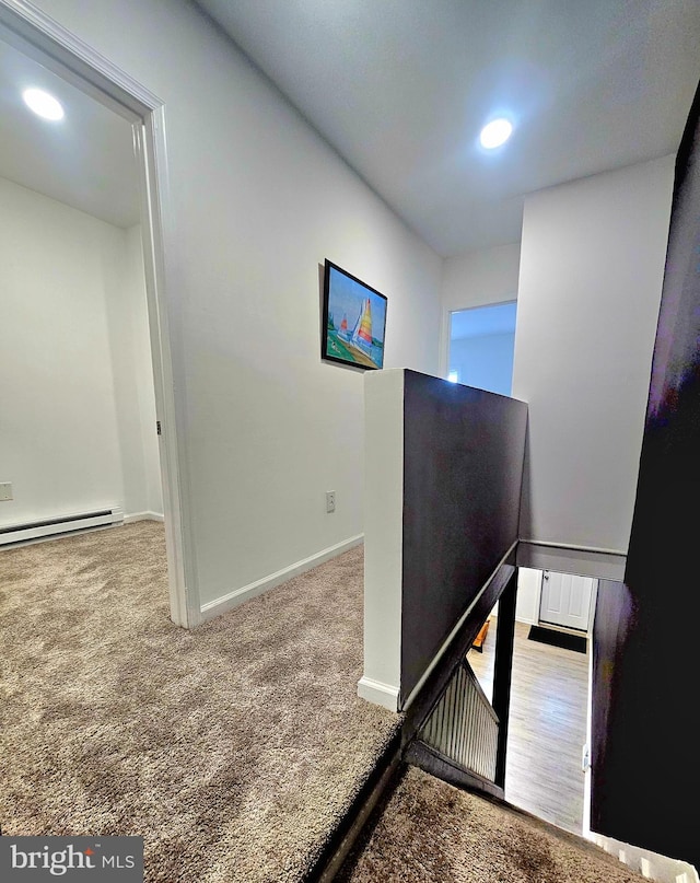 stairway featuring baseboard heating and carpet flooring