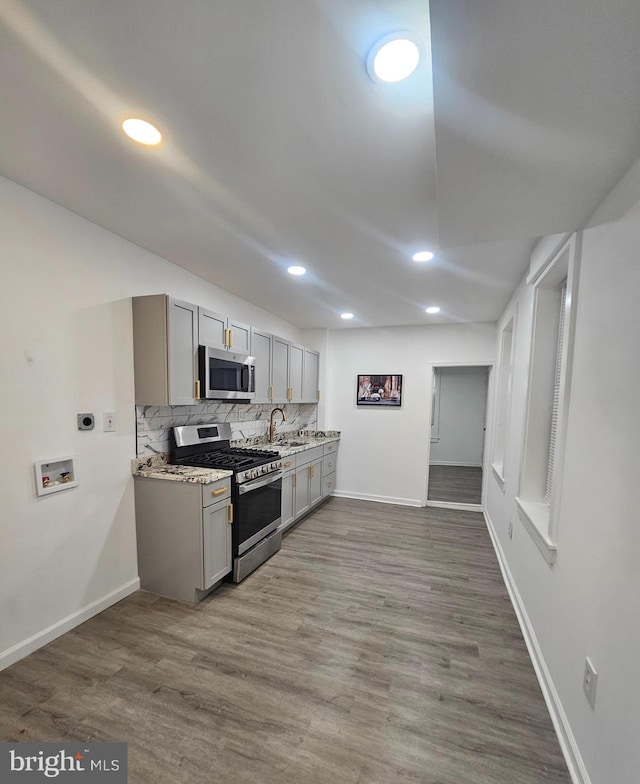 kitchen with gray cabinets, tasteful backsplash, light wood-type flooring, and stainless steel appliances