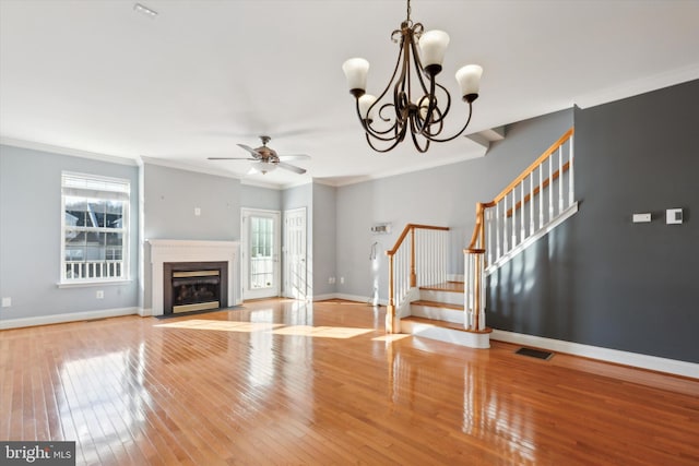 unfurnished living room featuring a wealth of natural light, crown molding, ceiling fan with notable chandelier, and light hardwood / wood-style flooring