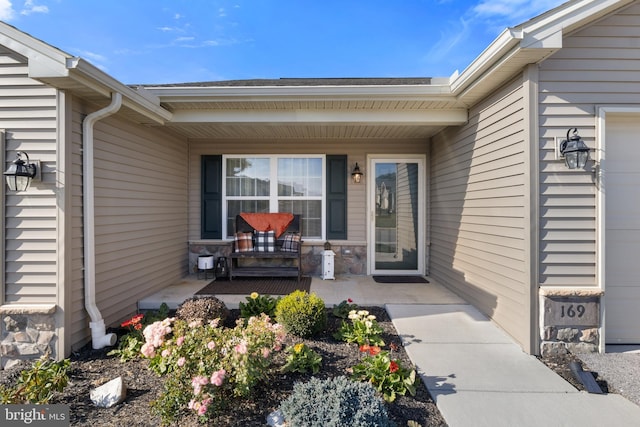 entrance to property featuring covered porch, stone siding, and a garage