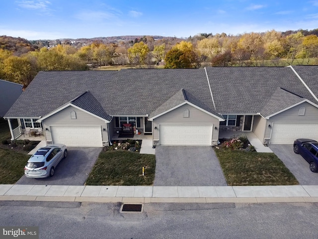 single story home featuring an attached garage, driveway, a front lawn, and roof with shingles