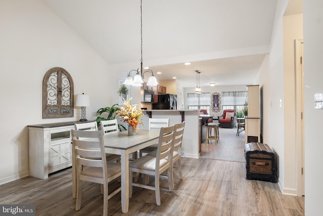 dining space with light wood-style floors, a chandelier, baseboards, high vaulted ceiling, and recessed lighting
