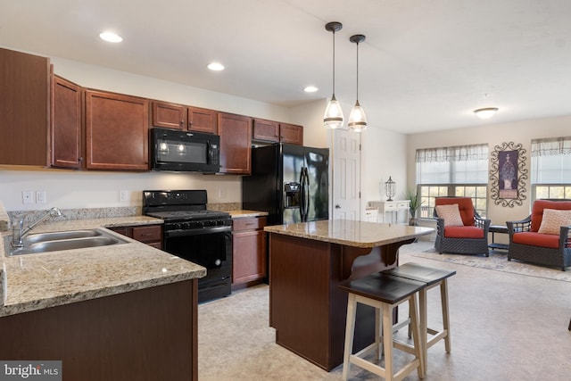 kitchen featuring black appliances, a sink, a kitchen bar, open floor plan, and a center island