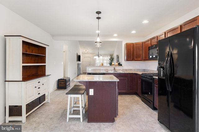 kitchen with black appliances, light stone counters, pendant lighting, a kitchen breakfast bar, and a center island