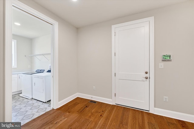 laundry area featuring washing machine and clothes dryer and light hardwood / wood-style floors