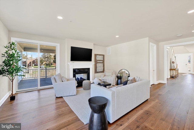 living room featuring a multi sided fireplace and hardwood / wood-style floors