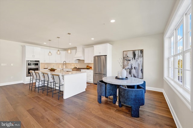 kitchen with pendant lighting, a healthy amount of sunlight, a center island with sink, and stainless steel appliances