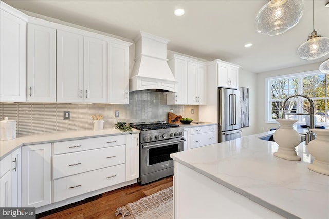 kitchen featuring custom exhaust hood, high end appliances, dark wood-type flooring, decorative light fixtures, and white cabinetry