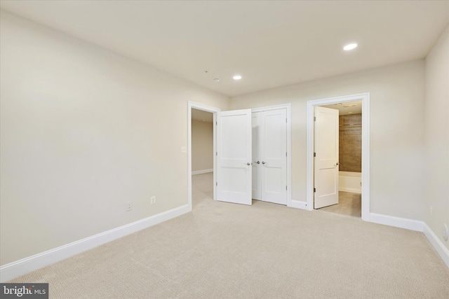 unfurnished bedroom featuring ensuite bath and light carpet