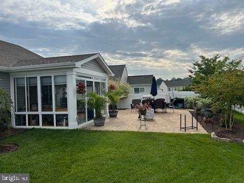 back of house featuring a patio, a sunroom, and a lawn