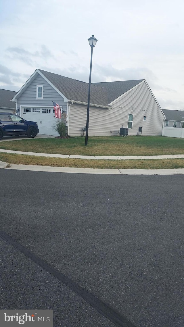 view of front of home with central AC, a garage, and a front lawn