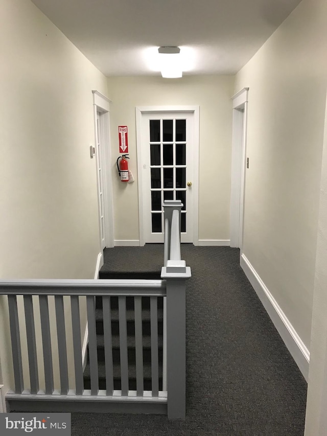 hallway with dark colored carpet