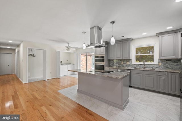 kitchen featuring gray cabinetry, a center island, light wood-type flooring, and island exhaust hood