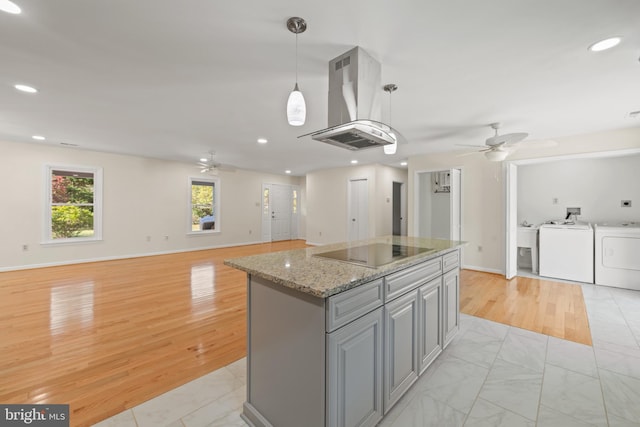 kitchen featuring island range hood, black electric cooktop, pendant lighting, light hardwood / wood-style flooring, and a kitchen island