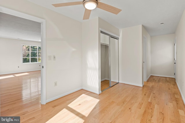 unfurnished bedroom with ceiling fan, a closet, and light wood-type flooring