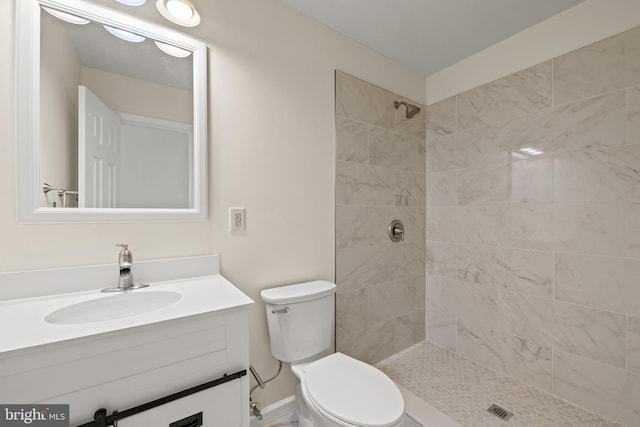 bathroom with tiled shower, vanity, and toilet