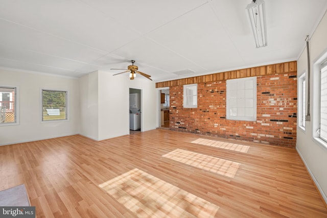 unfurnished living room featuring ceiling fan, plenty of natural light, light hardwood / wood-style floors, and brick wall