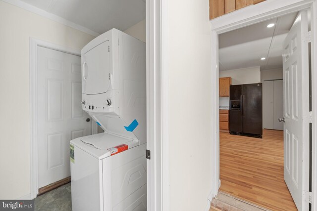 laundry room with light hardwood / wood-style floors and stacked washer / dryer