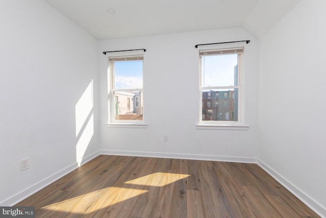 unfurnished room featuring vaulted ceiling and dark hardwood / wood-style flooring