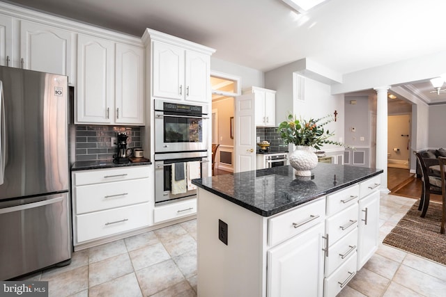 kitchen featuring stainless steel appliances, white cabinets, ornate columns, and tasteful backsplash