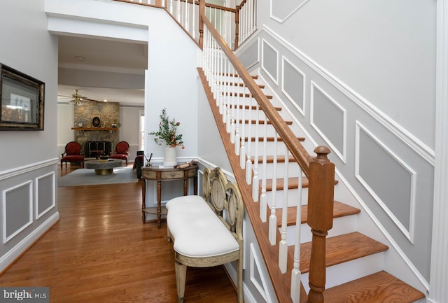 stairs featuring a fireplace, hardwood / wood-style flooring, and ornamental molding