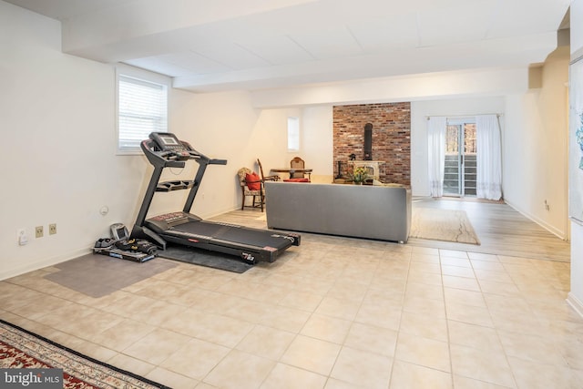 workout area featuring a wood stove, light hardwood / wood-style floors, and plenty of natural light