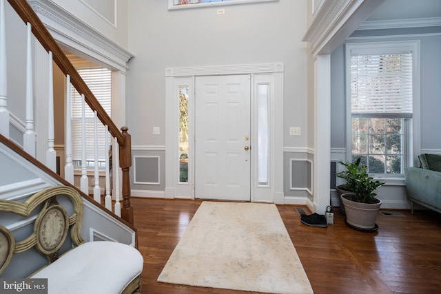 entryway featuring a high ceiling, a healthy amount of sunlight, dark hardwood / wood-style flooring, and ornamental molding