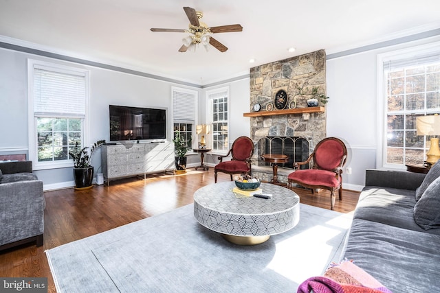 living room with dark wood-type flooring, a fireplace, ceiling fan, and ornamental molding