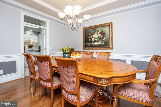 dining room featuring wood-type flooring, ornamental molding, and a notable chandelier