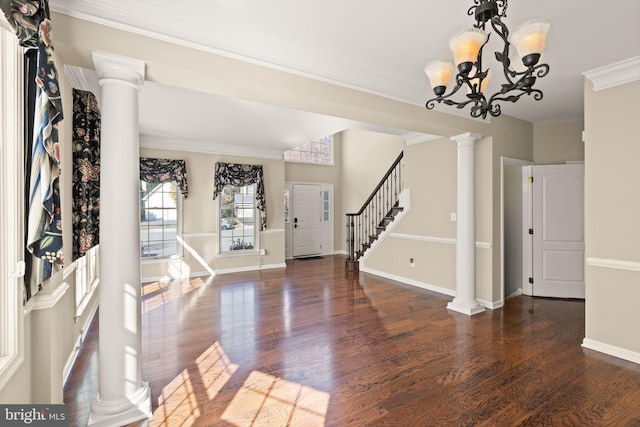 foyer featuring ornamental molding, dark hardwood / wood-style floors, a chandelier, and decorative columns