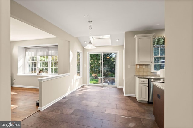 kitchen featuring white cabinets, stainless steel dishwasher, and a healthy amount of sunlight