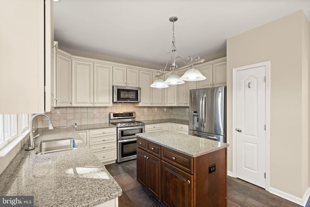 kitchen featuring light stone counters, a center island, hanging light fixtures, sink, and appliances with stainless steel finishes