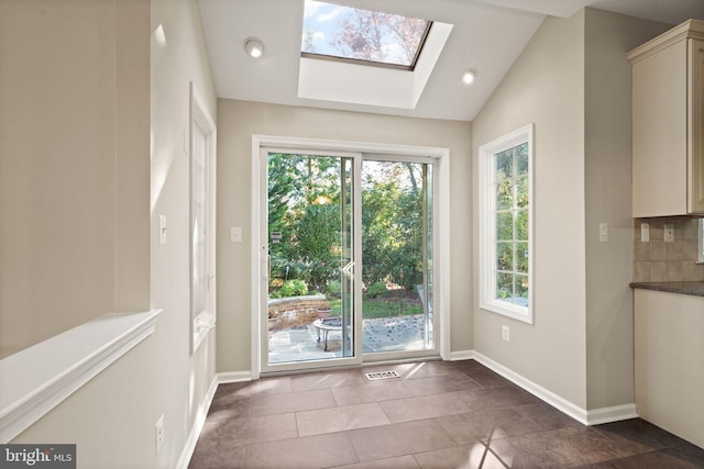 doorway with vaulted ceiling with skylight and tile patterned floors