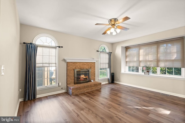 unfurnished living room with ceiling fan, dark hardwood / wood-style floors, and a brick fireplace