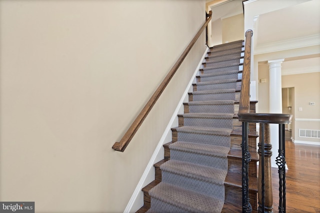 stairway featuring hardwood / wood-style floors, crown molding, and decorative columns