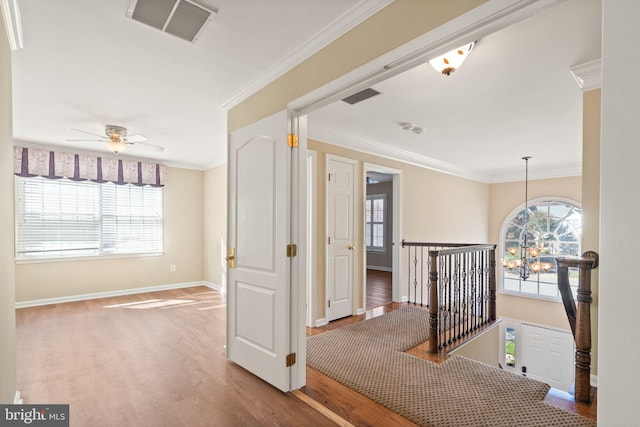 hall featuring ornamental molding, wood-type flooring, and a notable chandelier