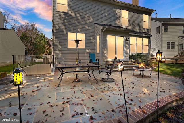 back house at dusk featuring a patio area