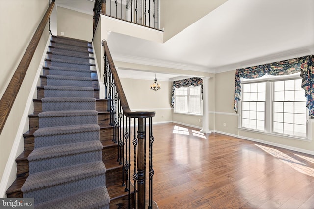 stairs featuring wood-type flooring, a chandelier, and ornamental molding