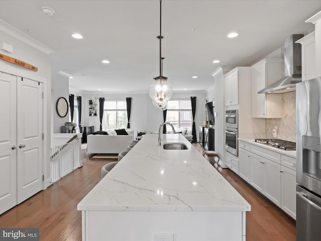 kitchen featuring wall chimney exhaust hood, sink, dark wood-type flooring, and decorative light fixtures