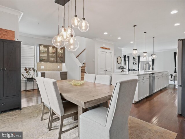 dining room featuring dark wood-type flooring, crown molding, and sink