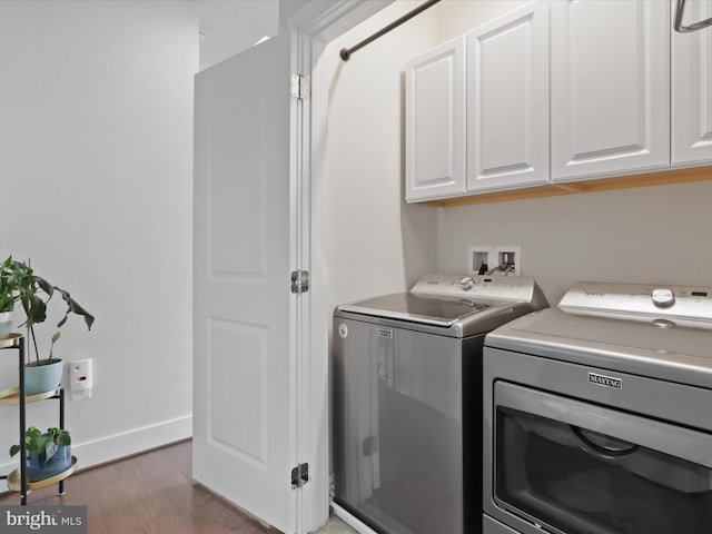 laundry room featuring dark hardwood / wood-style flooring, washing machine and clothes dryer, and cabinets