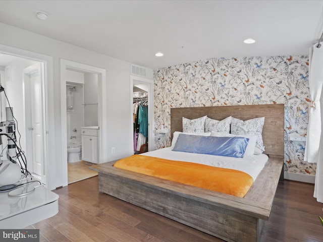 bedroom featuring a walk in closet, dark hardwood / wood-style floors, a closet, and ensuite bath