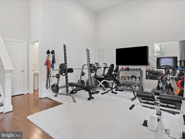 workout area featuring hardwood / wood-style floors and a high ceiling