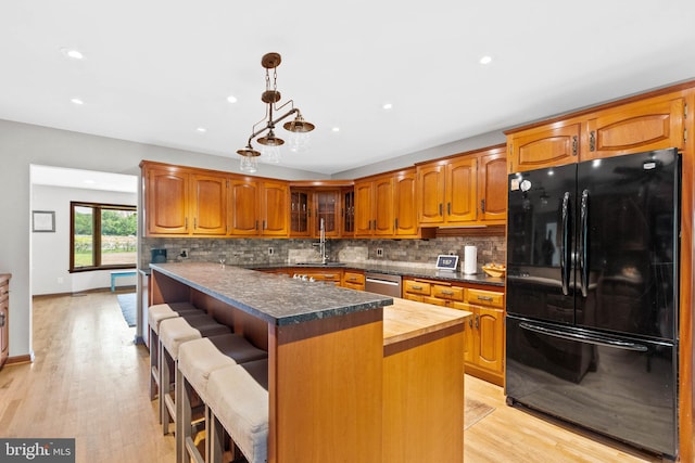 kitchen featuring light hardwood / wood-style floors, a kitchen bar, a kitchen island, and black refrigerator