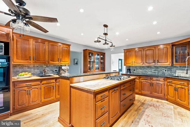 kitchen featuring stainless steel gas cooktop, black oven, a center island, and light wood-type flooring