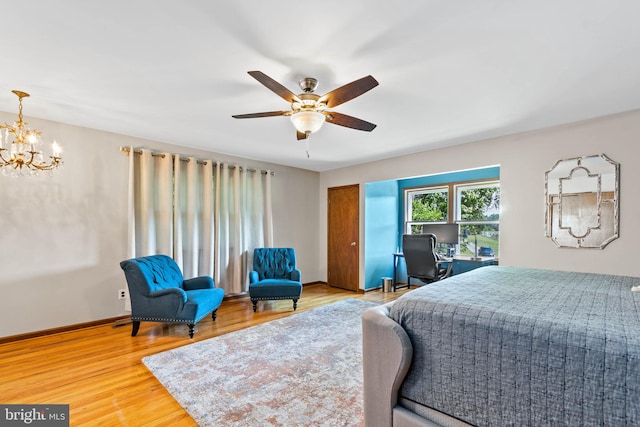 bedroom with ceiling fan with notable chandelier and hardwood / wood-style floors