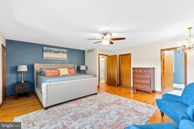 bedroom featuring light hardwood / wood-style floors and ceiling fan with notable chandelier