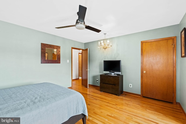 bedroom with wood-type flooring and ceiling fan with notable chandelier